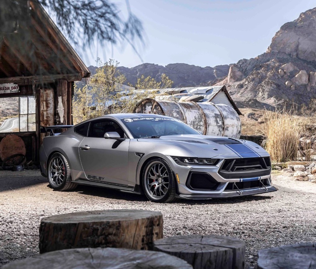 Silver Shelby Super Snake with blue racing stripes at a desert outpost